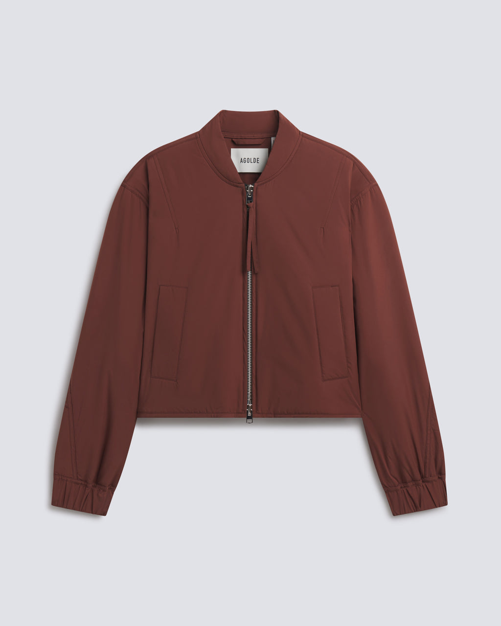 A cropped bomber jacket in a muted reddish-brown color, featuring a front zipper, ribbed cuffs, and side pockets, displayed on a light gray background.