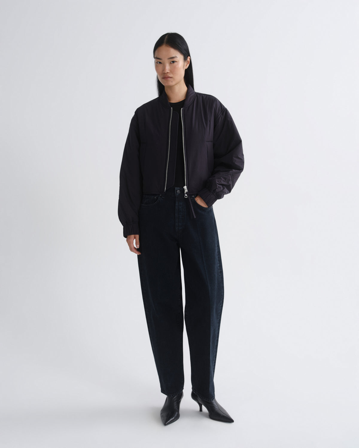 Person wearing a black bomber jacket and pants on a white background