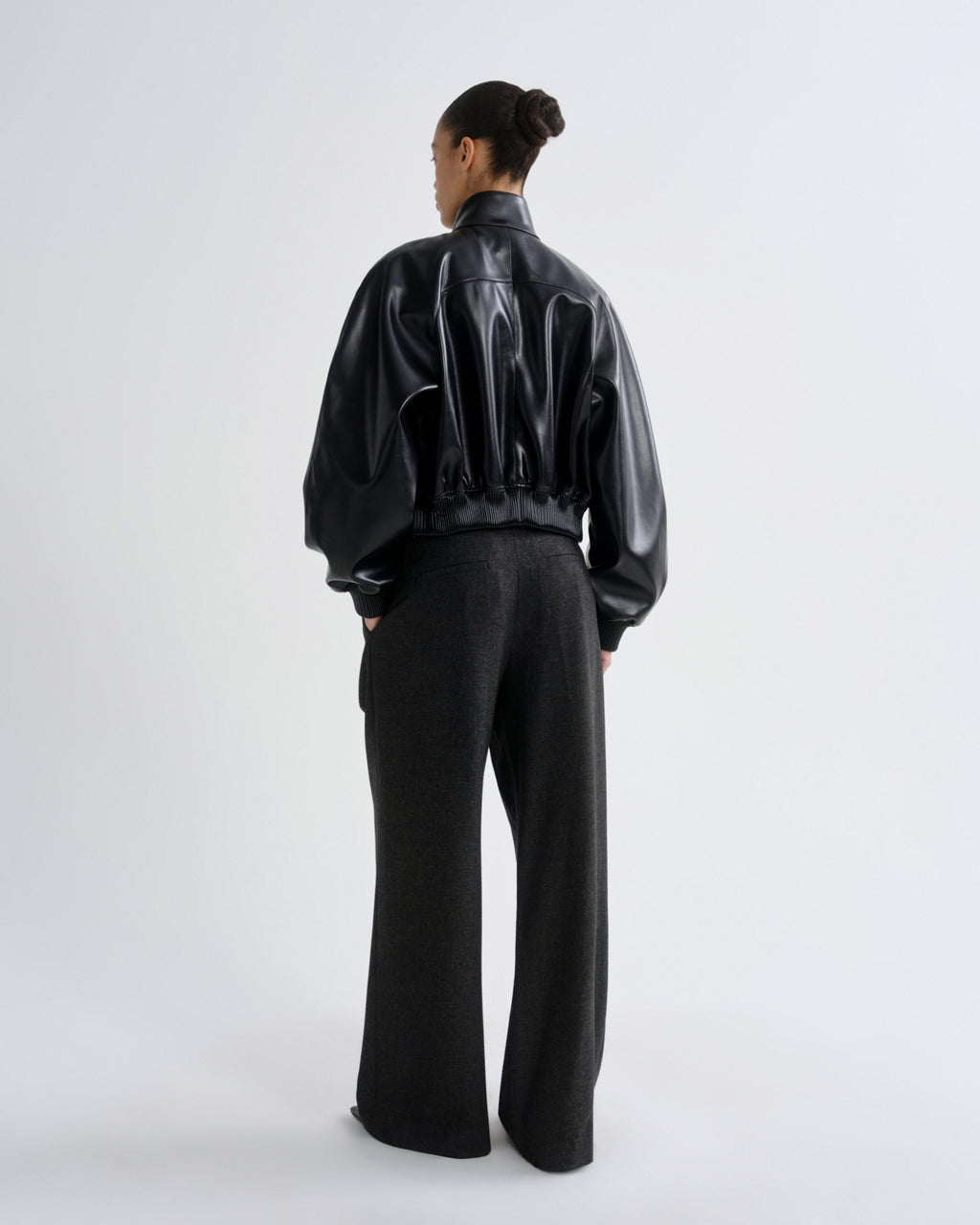 Person wearing a black vinyl jacket and pants on a white background