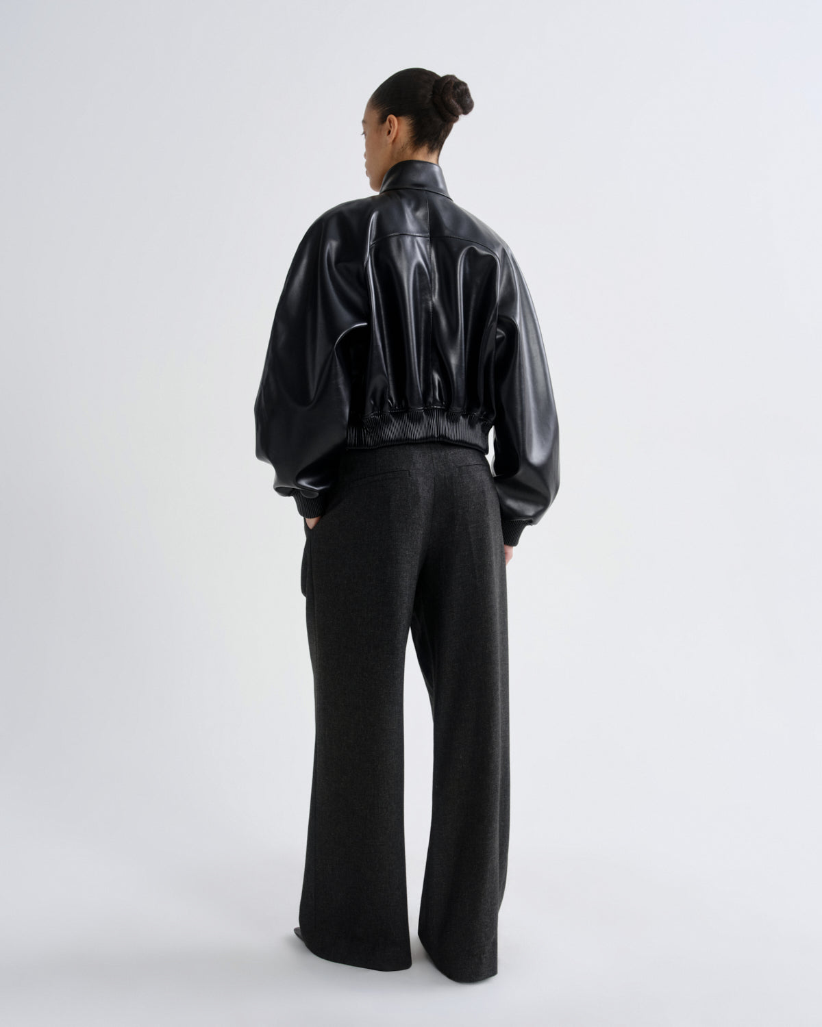 Person wearing a black vinyl jacket and pants on a white background