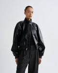 Person wearing a black leather jacket and pants on a white background