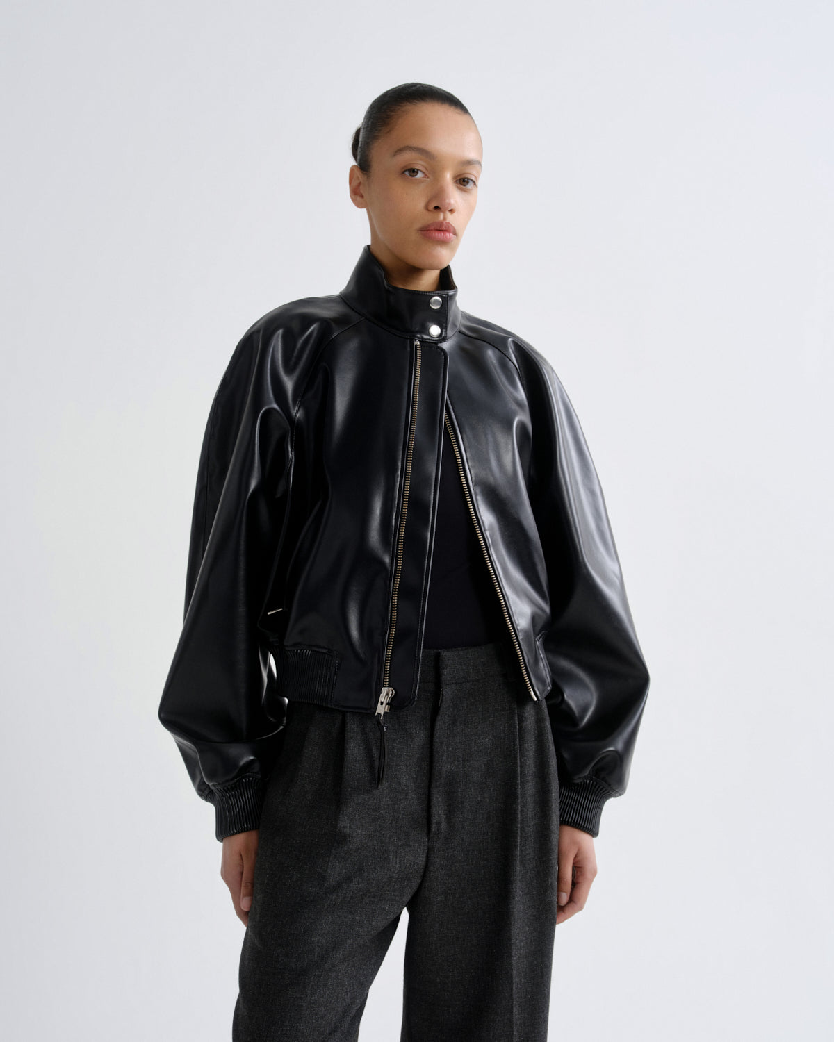 Person wearing a black leather jacket and pants on a white background