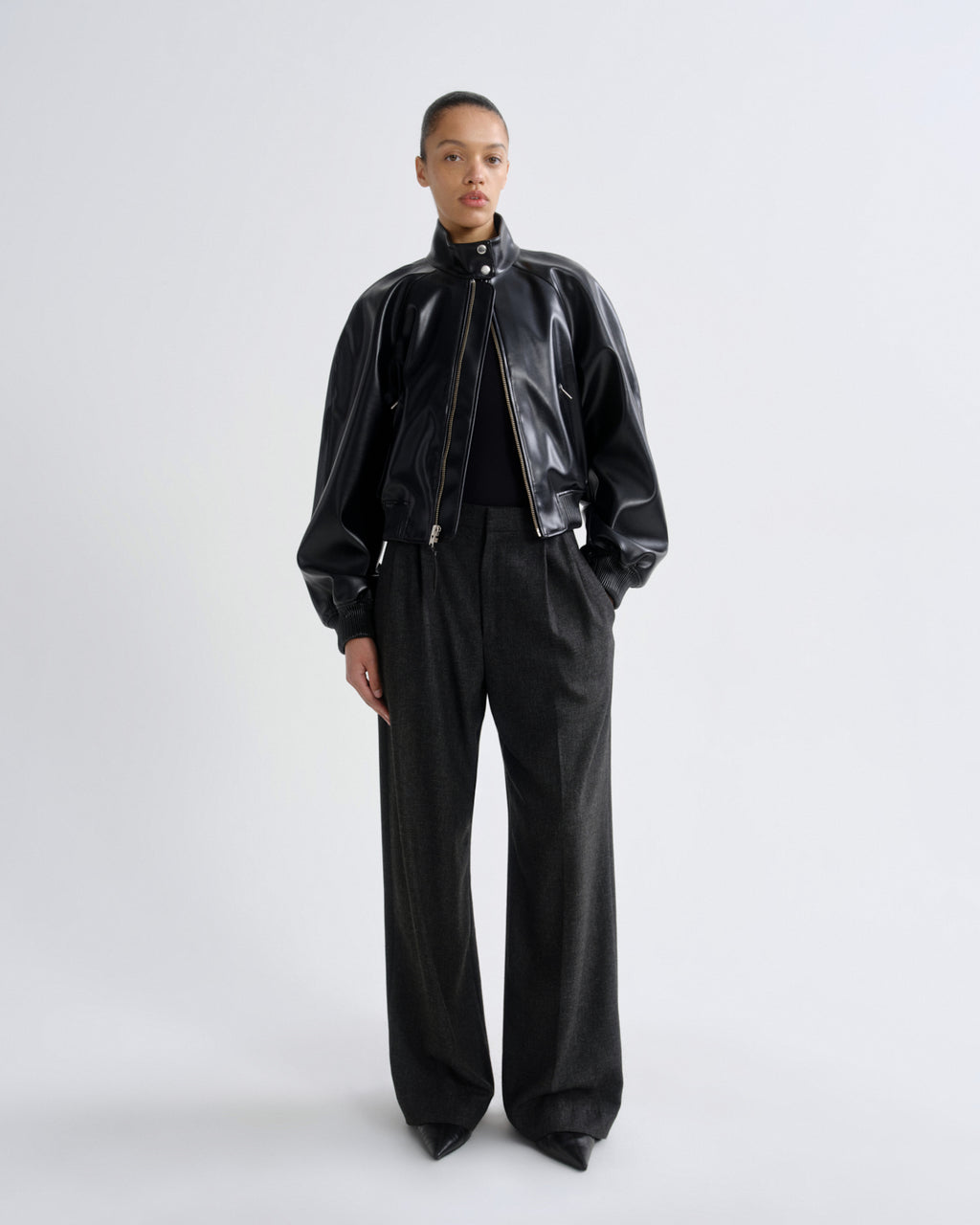 Person wearing a black leather jacket and pants on a white background