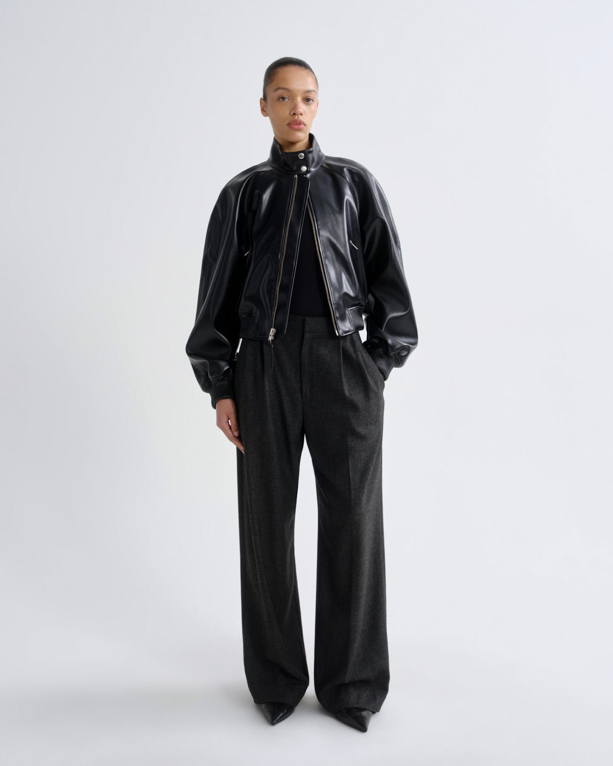 Person wearing a black leather jacket and pants on a white background