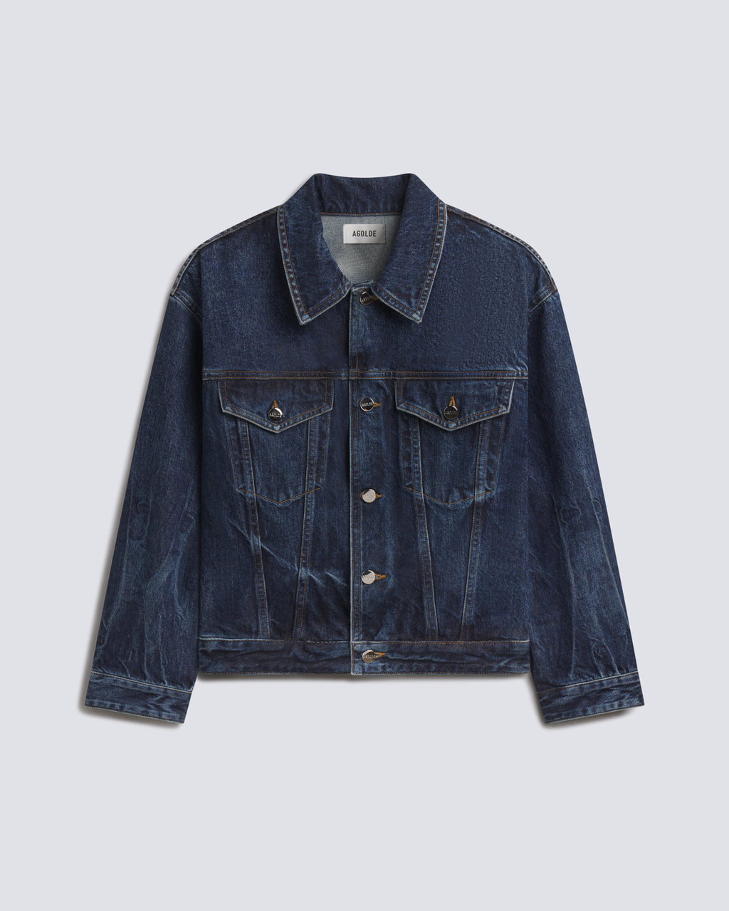 A dark blue denim trucker jacket with a pointed collar, button-up front, and flap chest pockets, displayed flat against a light gray background.
