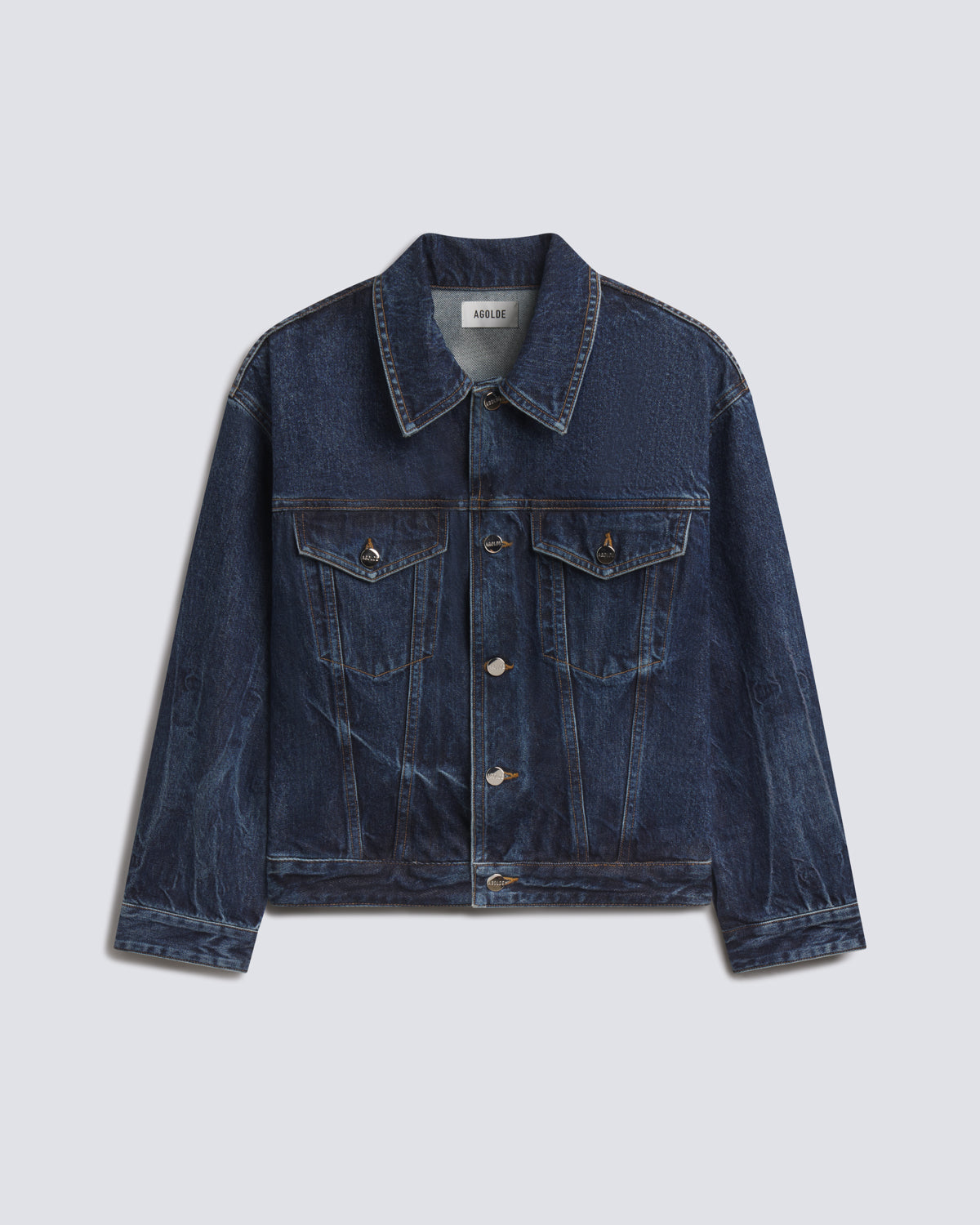 A dark blue denim trucker jacket with a pointed collar, button-up front, and flap chest pockets, displayed flat against a light gray background.