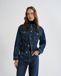 Person wearing a blue denim jacket and jeans on a white background