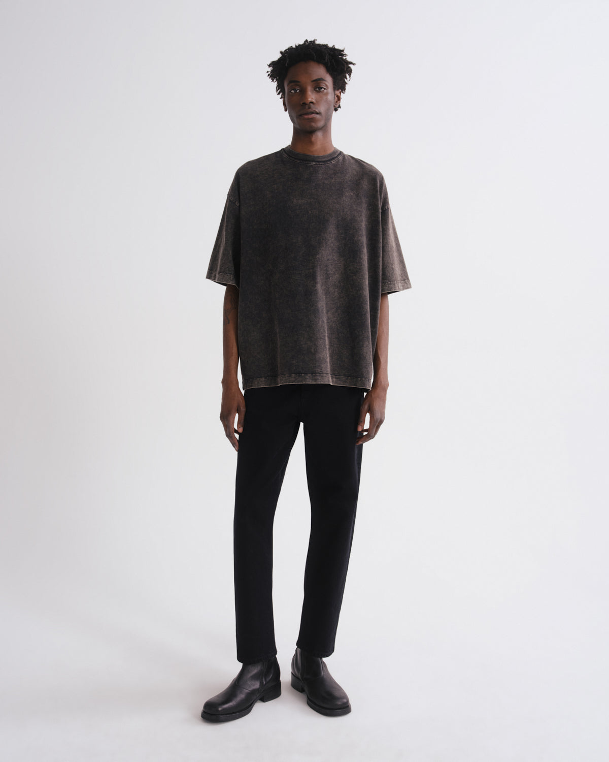 Person wearing a dark t-shirt and black pants on a white background