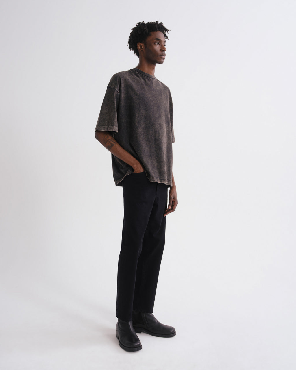 Person wearing a dark gray oversized shirt and black pants on a white background