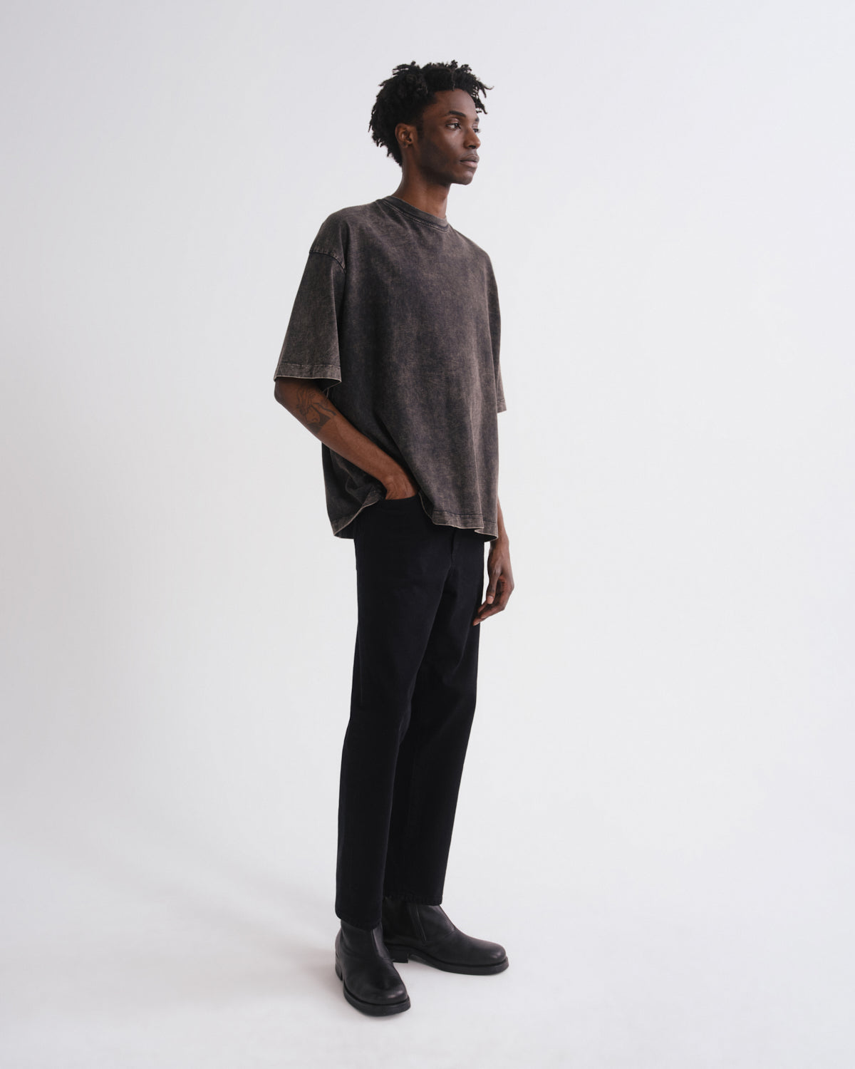 Person wearing a dark gray oversized shirt and black pants on a white background