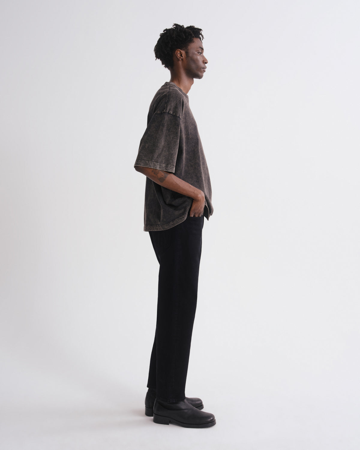 Person wearing a dark gray shirt and black pants on a white background