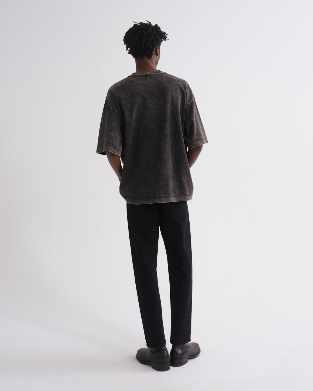 Person wearing a dark t-shirt and black pants on a white background