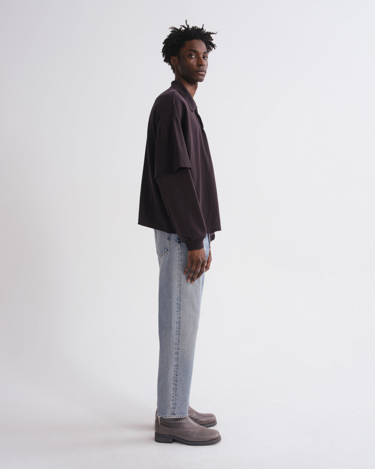 Man wearing a dark shirt and light jeans on a white background