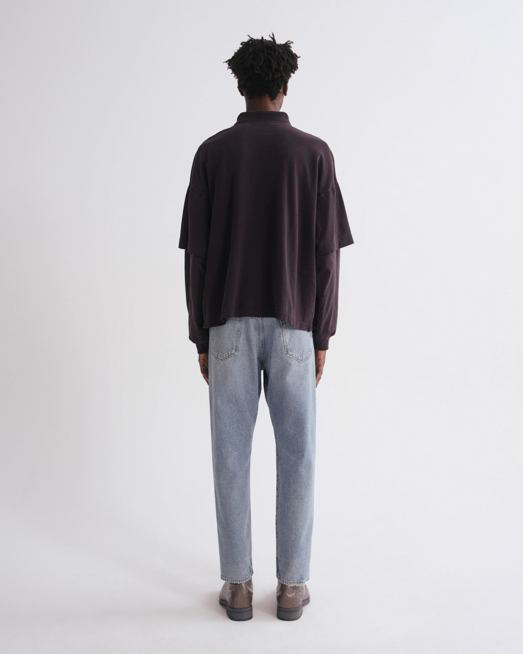 Person wearing a dark shirt and light blue jeans on a white background
