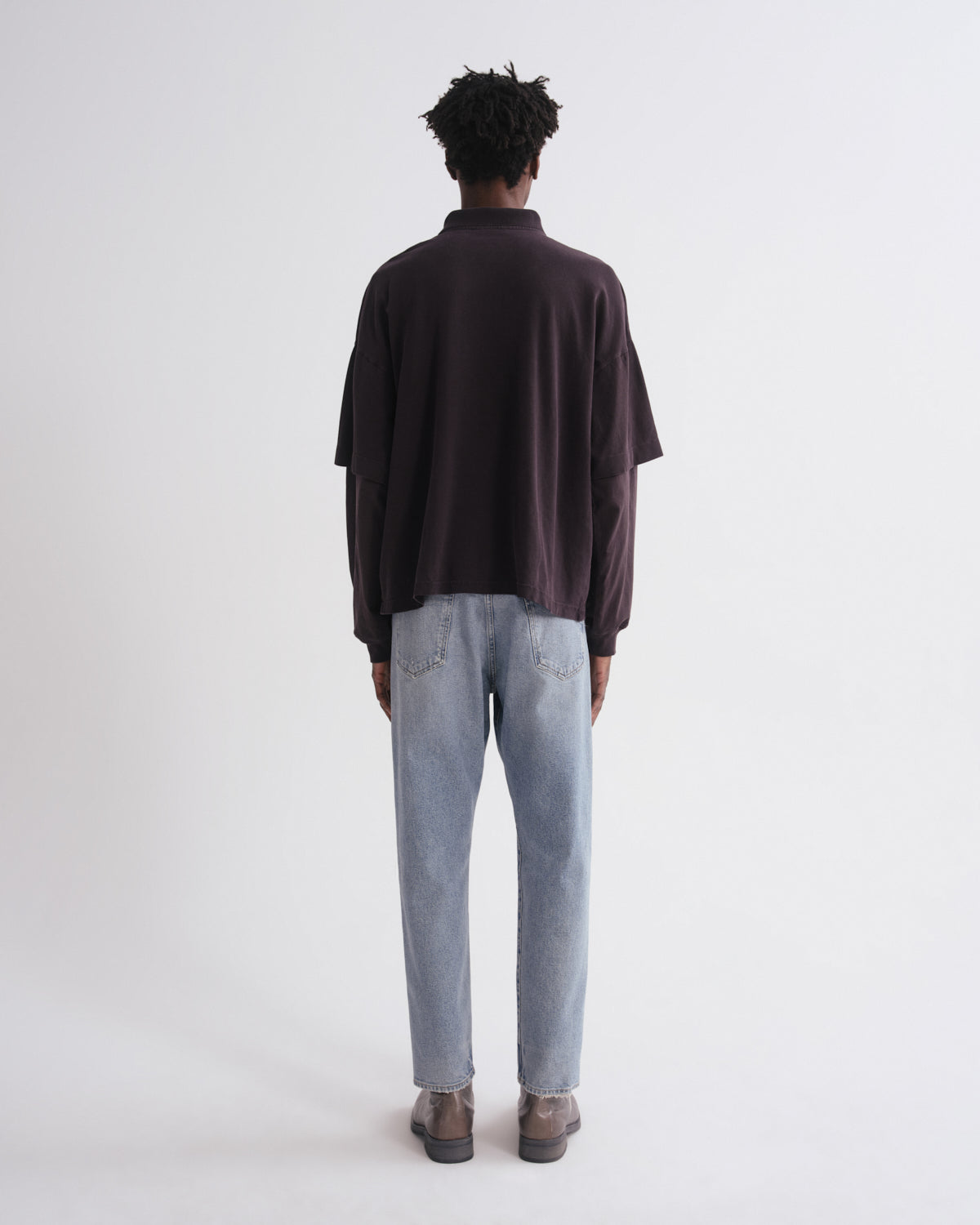 Person wearing a dark shirt and light blue jeans on a white background