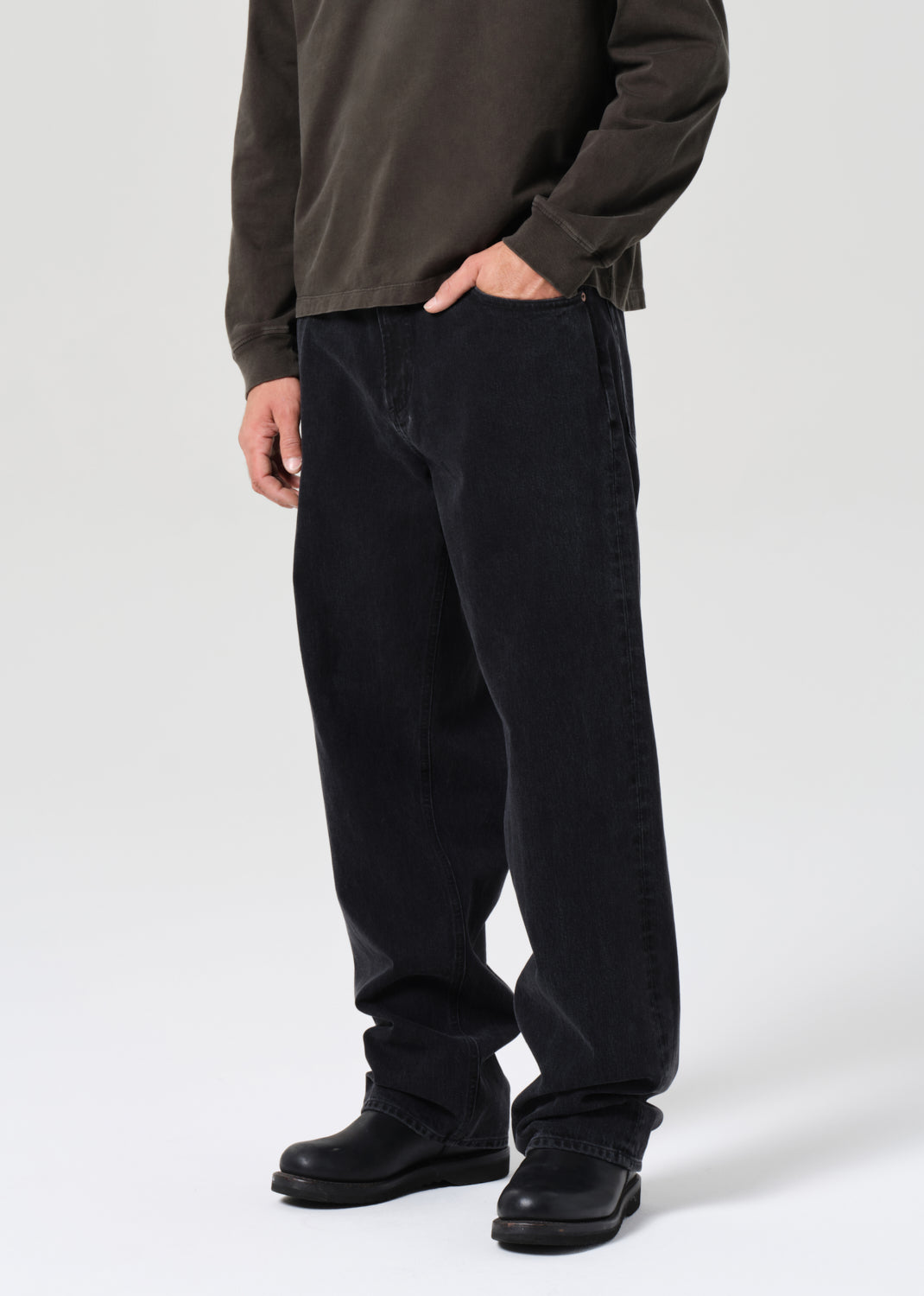 Person wearing black pants and a brown jacket on a white background