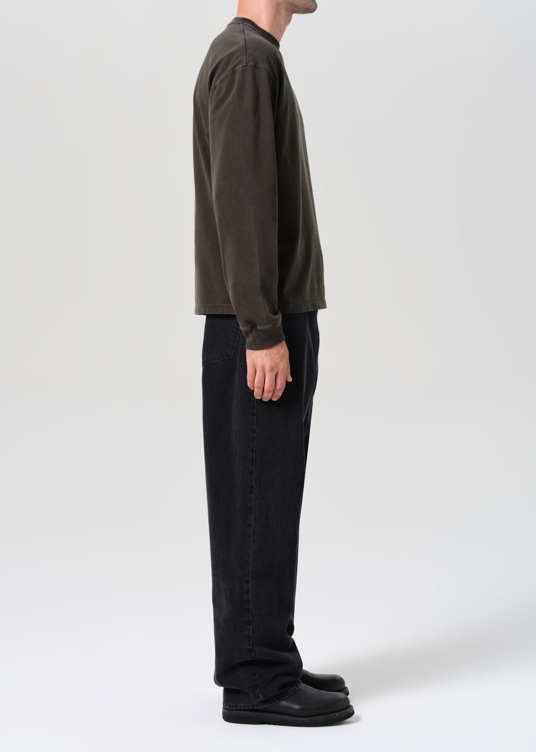 Person wearing a dark long-sleeve shirt and black pants on a white background