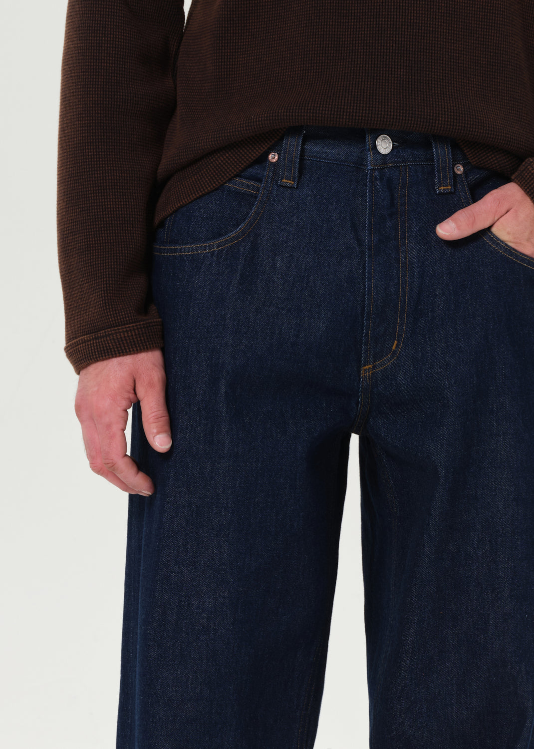 Person wearing dark blue jeans with a plain background