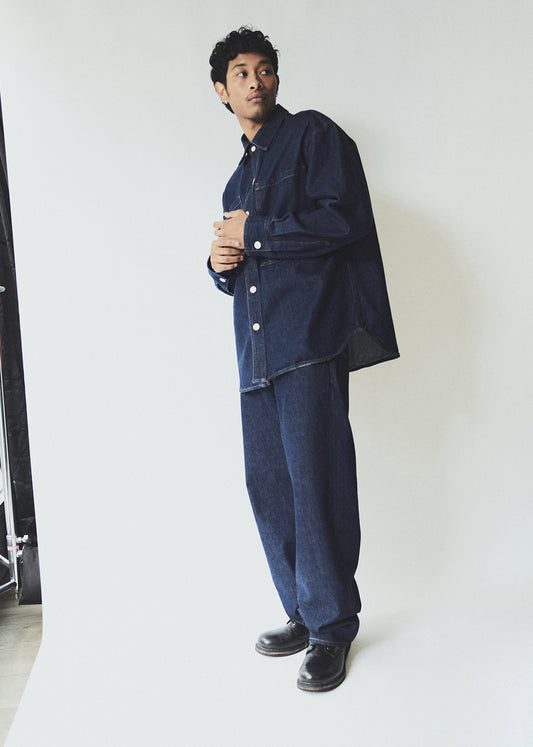 Man wearing a dark denim outfit against a white background