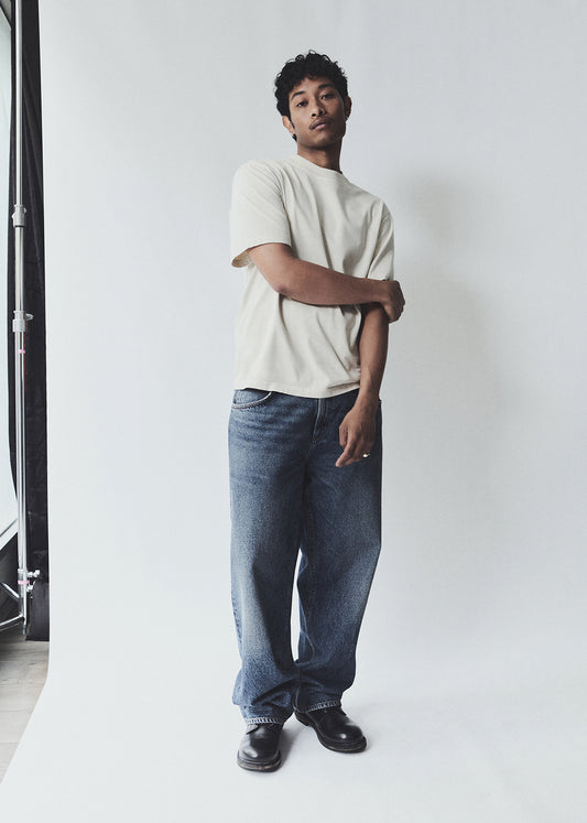Person wearing a white t-shirt and blue jeans standing against a plain white background