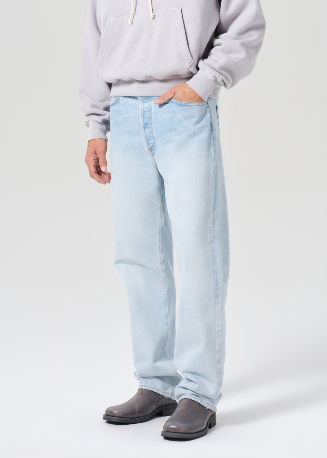 Person wearing light blue jeans and a gray sweatshirt on a white background