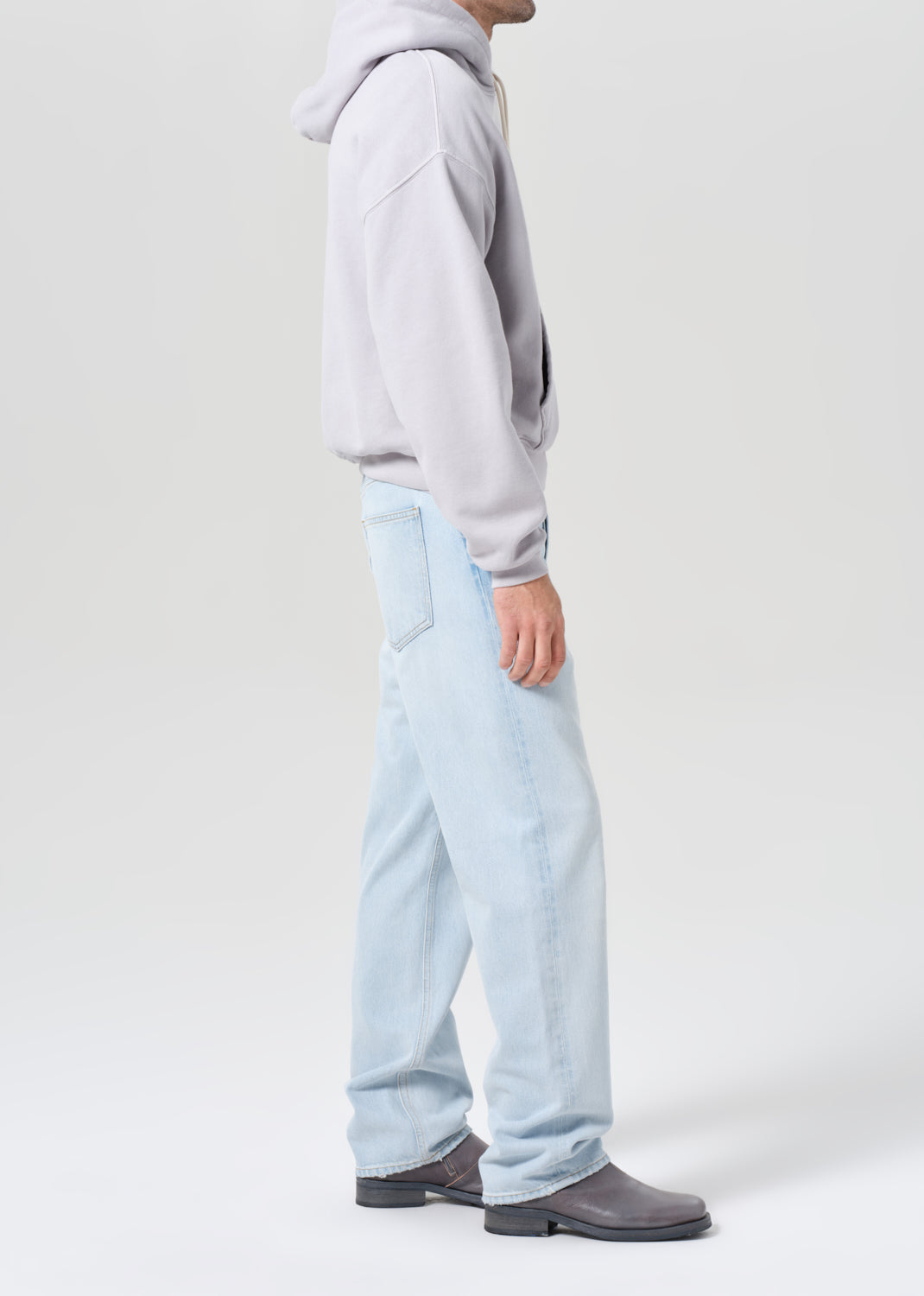Person wearing a gray hoodie and light blue pants on a white background