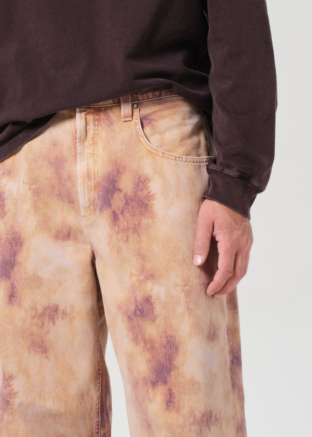 Person wearing tie-dye pants with a plain background