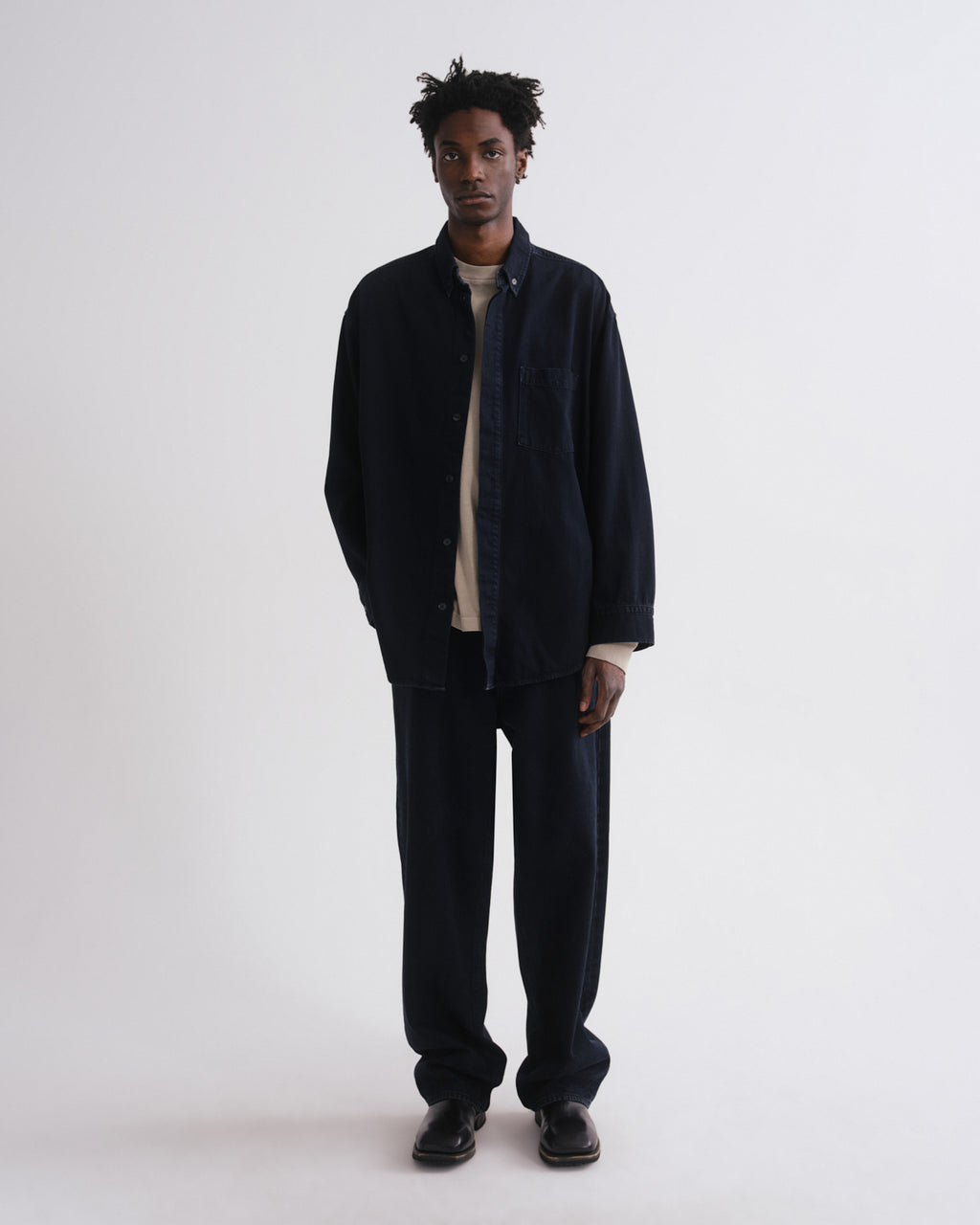 Person wearing a dark jacket and pants on a grey background