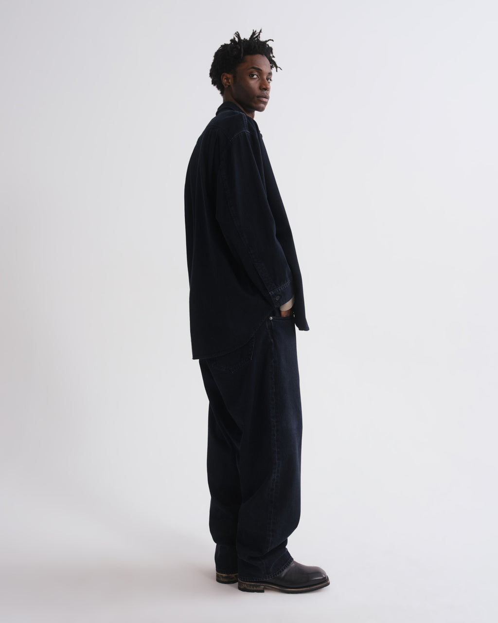 Person wearing a dark suit standing against a grey background