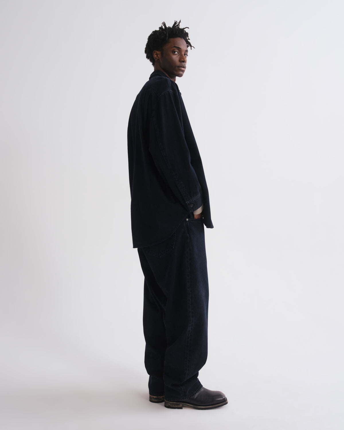 Person wearing a dark suit standing against a grey background