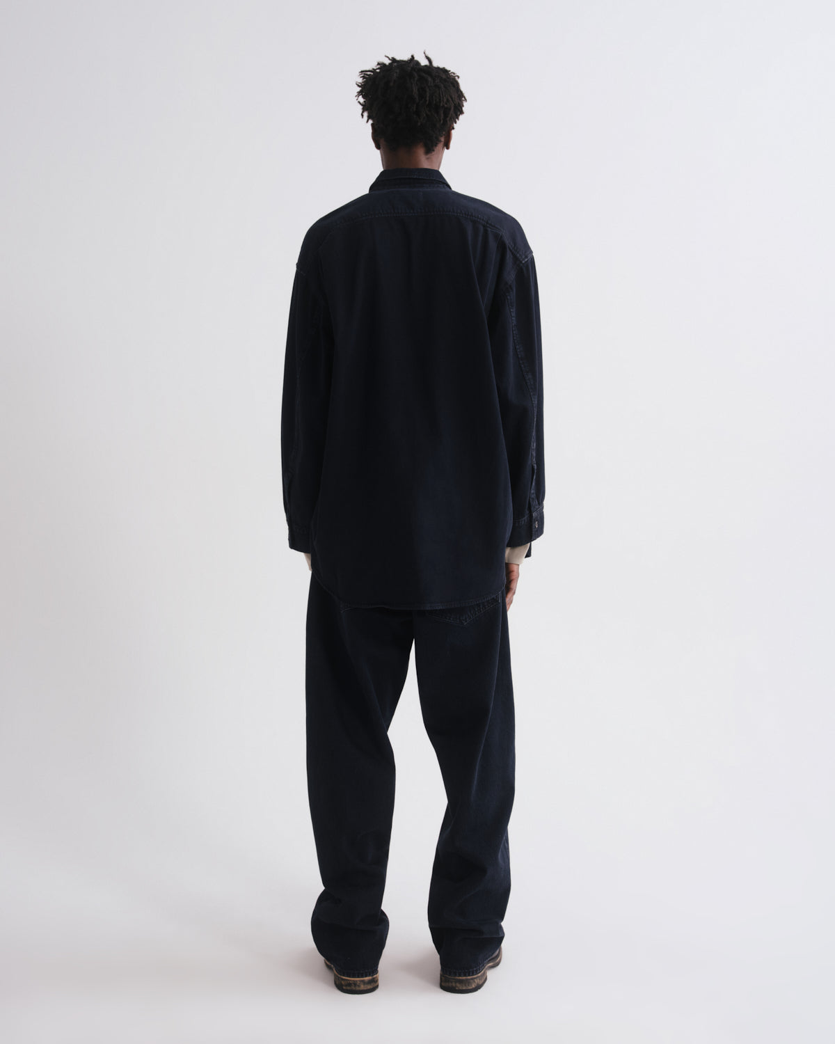 Person wearing a dark blue outfit on a grey background