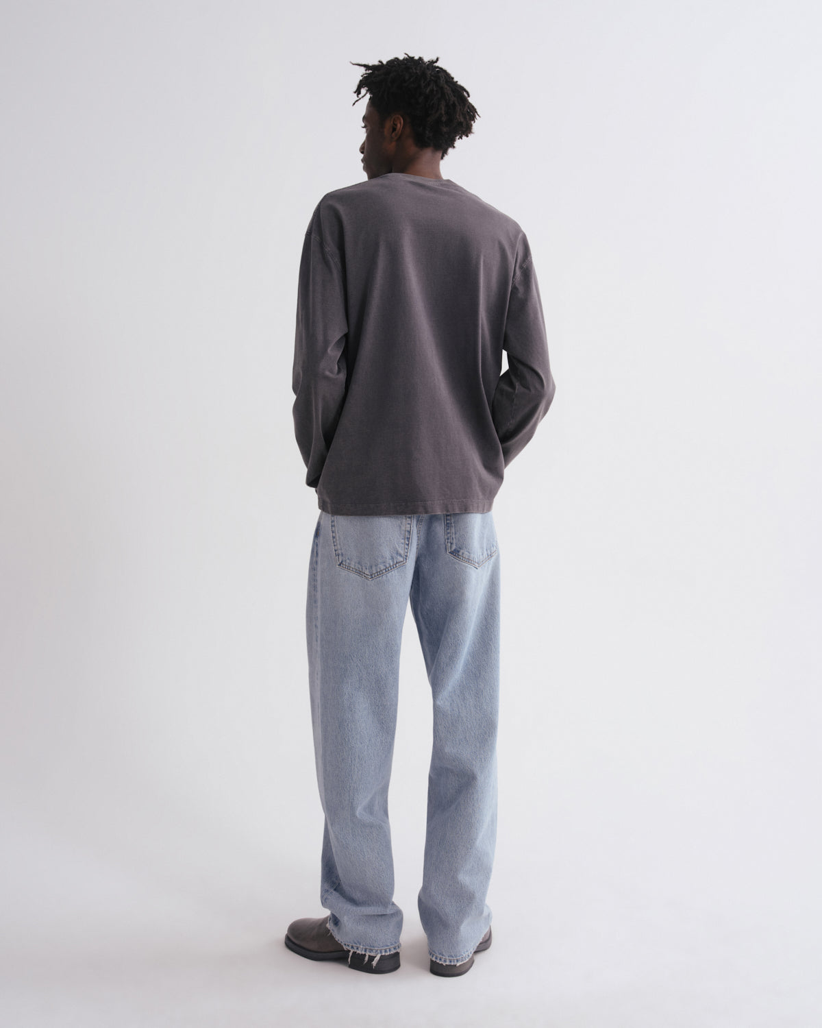 Person wearing a gray sweater and light blue jeans on a white background