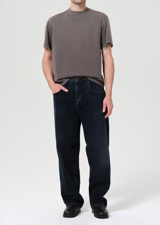 Person wearing a grey shirt and dark blue jeans on a white background