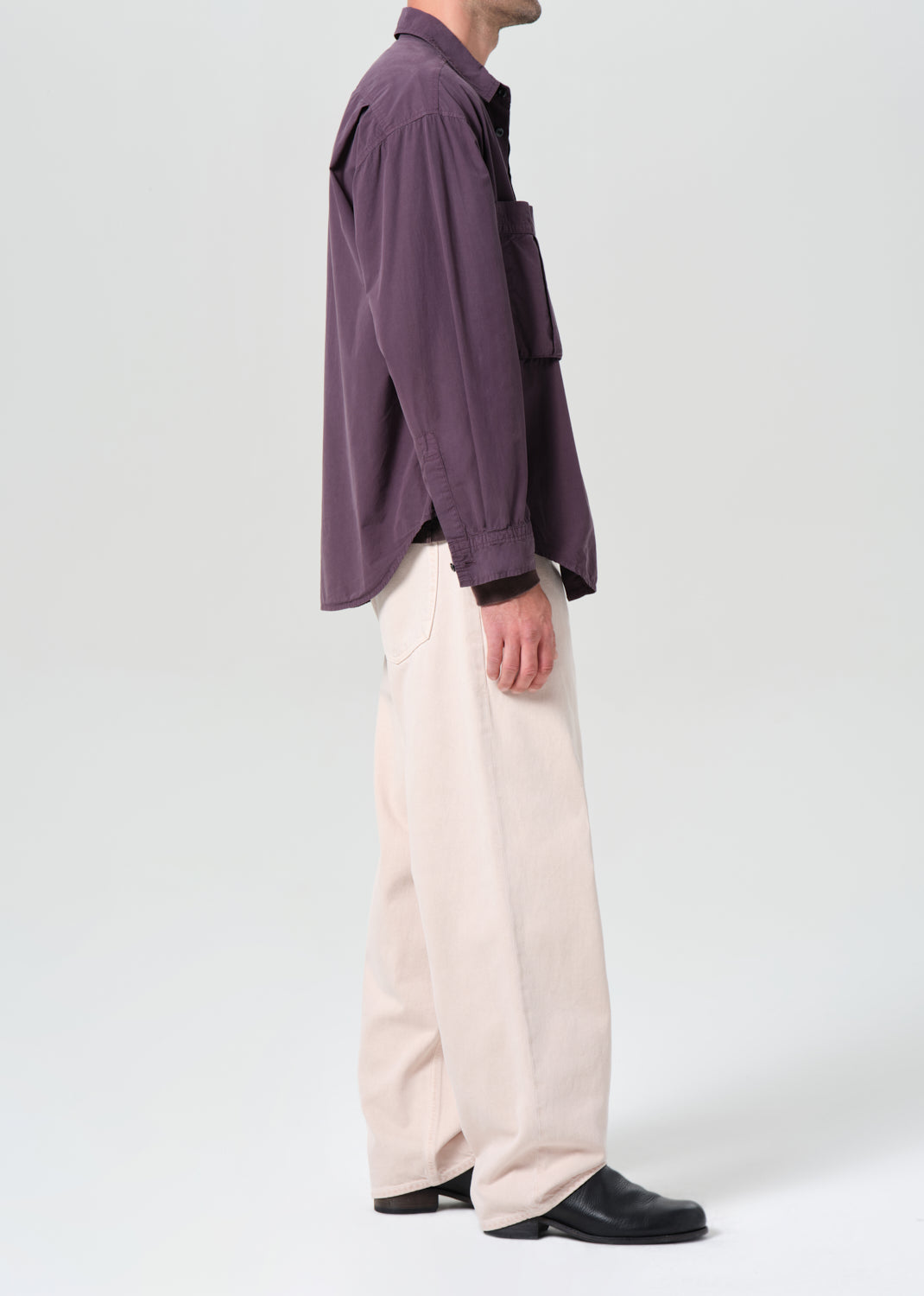 Person wearing a purple shirt and beige pants on a white background