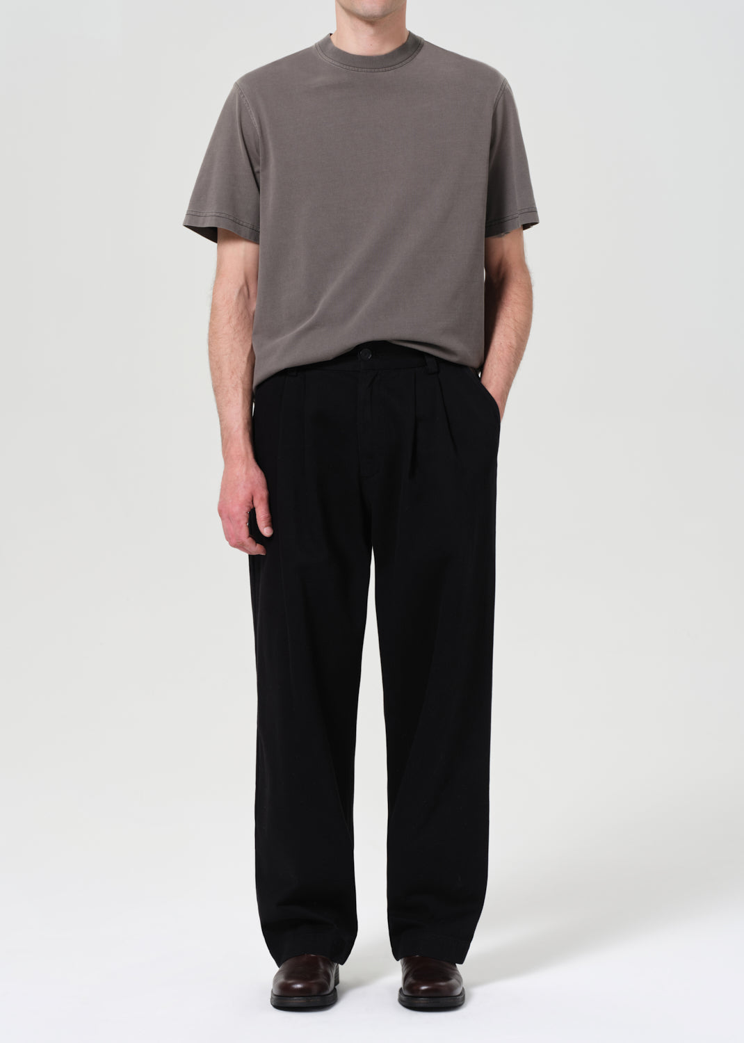 Person wearing a gray t-shirt and black pants on a white background