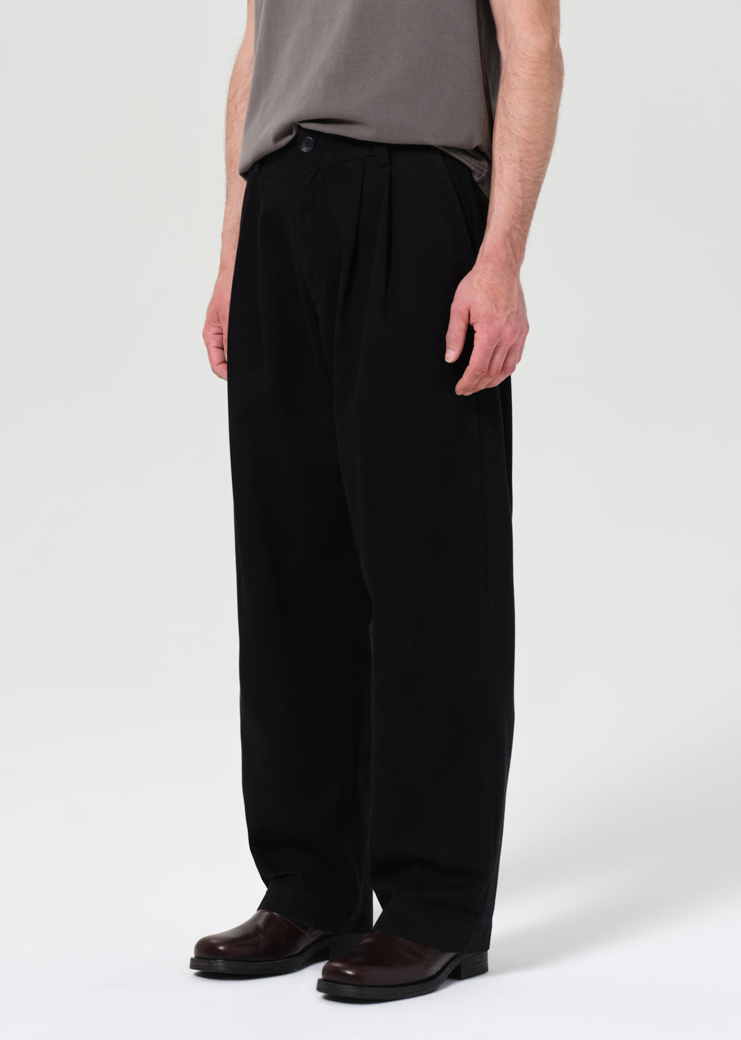 Person wearing black wide-leg pants and a gray top on a white background