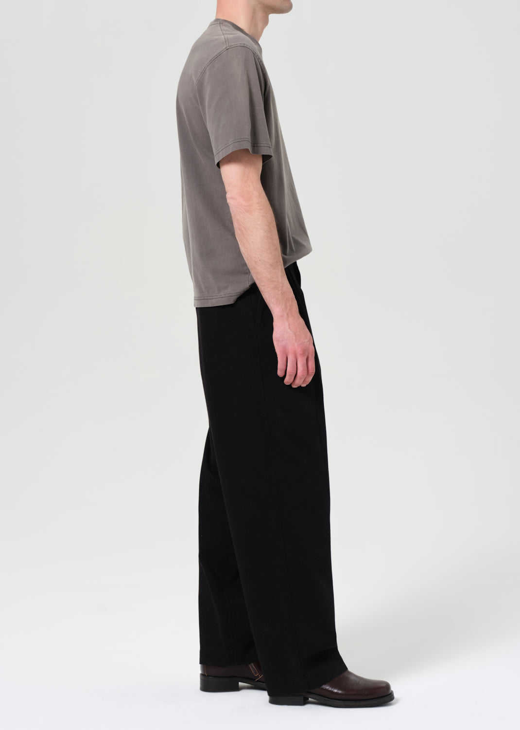 Person wearing a gray t-shirt and black pants on a white background