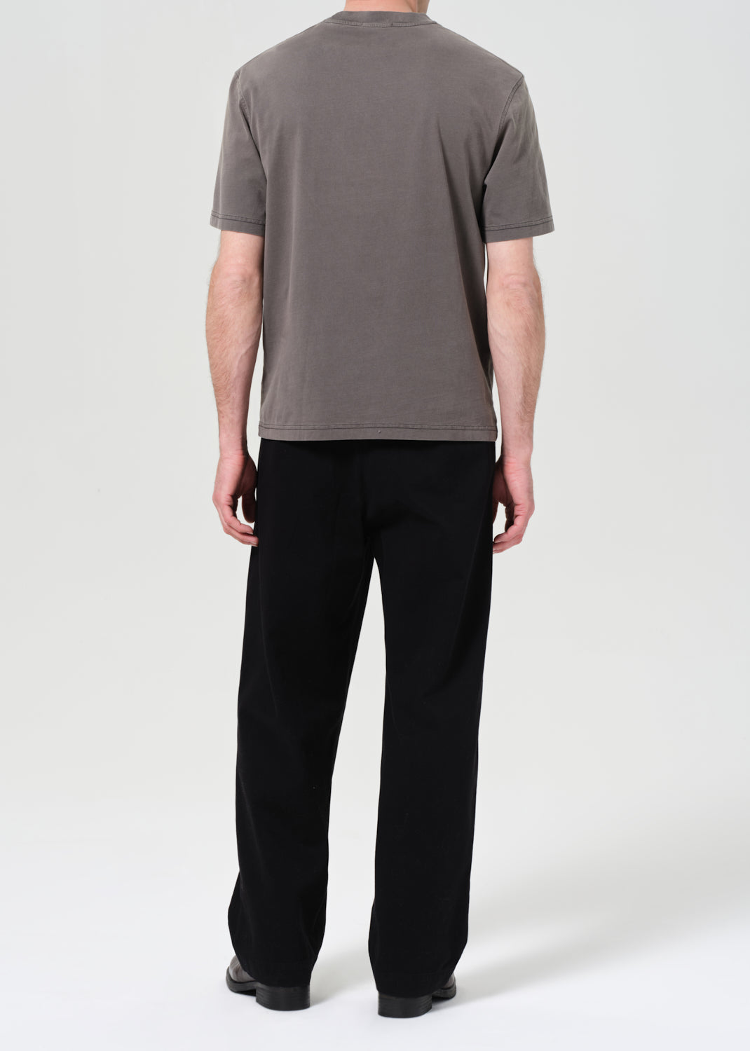 Person wearing a gray t-shirt and black pants on a white background