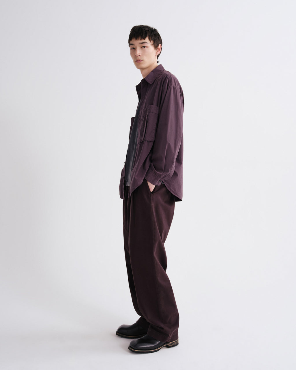 Person wearing a dark purple outfit on a grey background