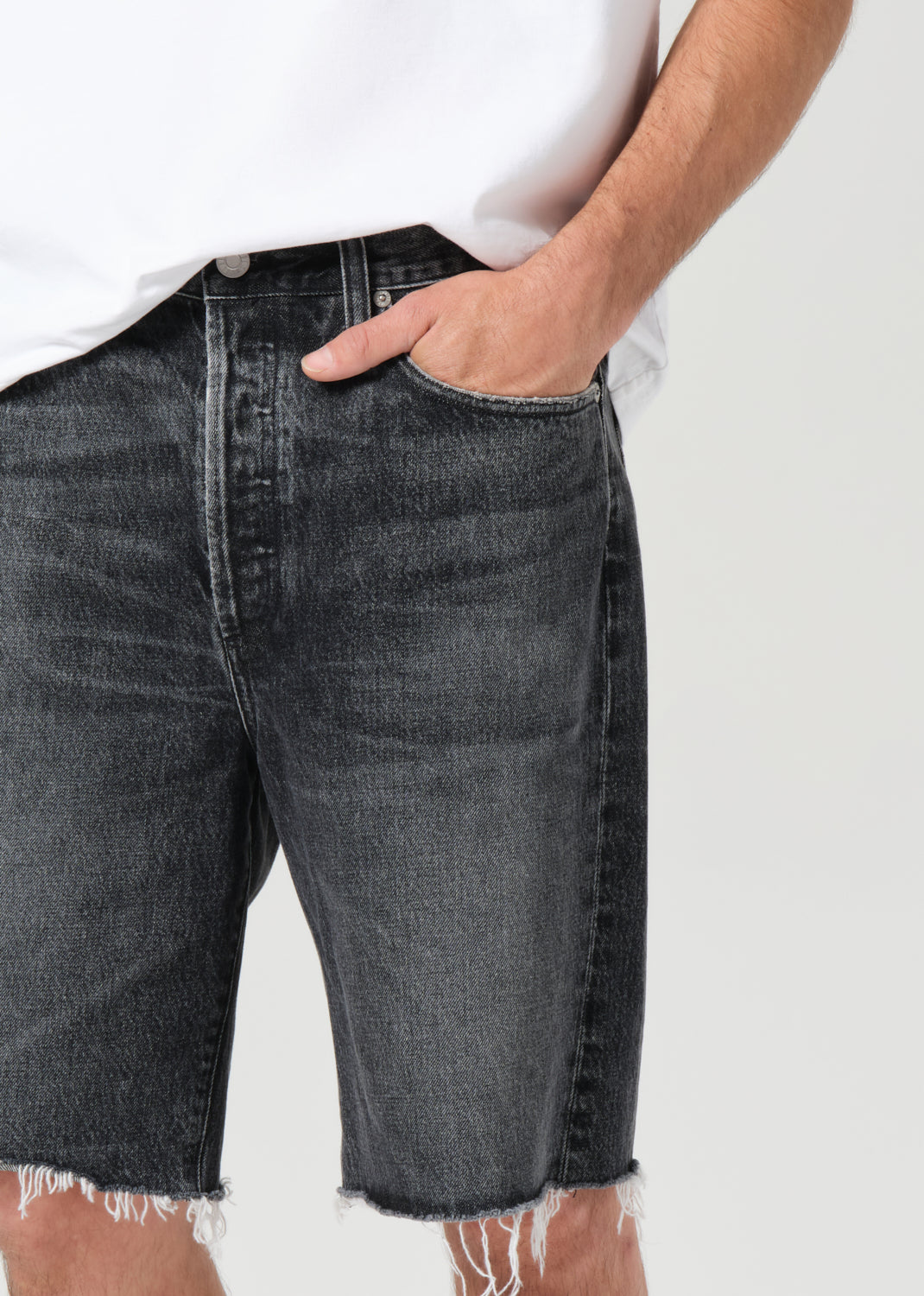 Person wearing black denim shorts with a white background