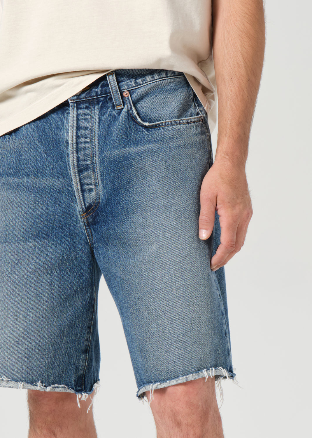 Person wearing blue denim shorts on a plain background