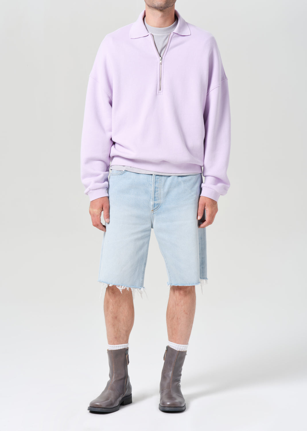 Person wearing a light purple sweater, light blue denim shorts, and gray boots on a white background