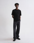Person wearing a black t-shirt and dark jeans on a white background
