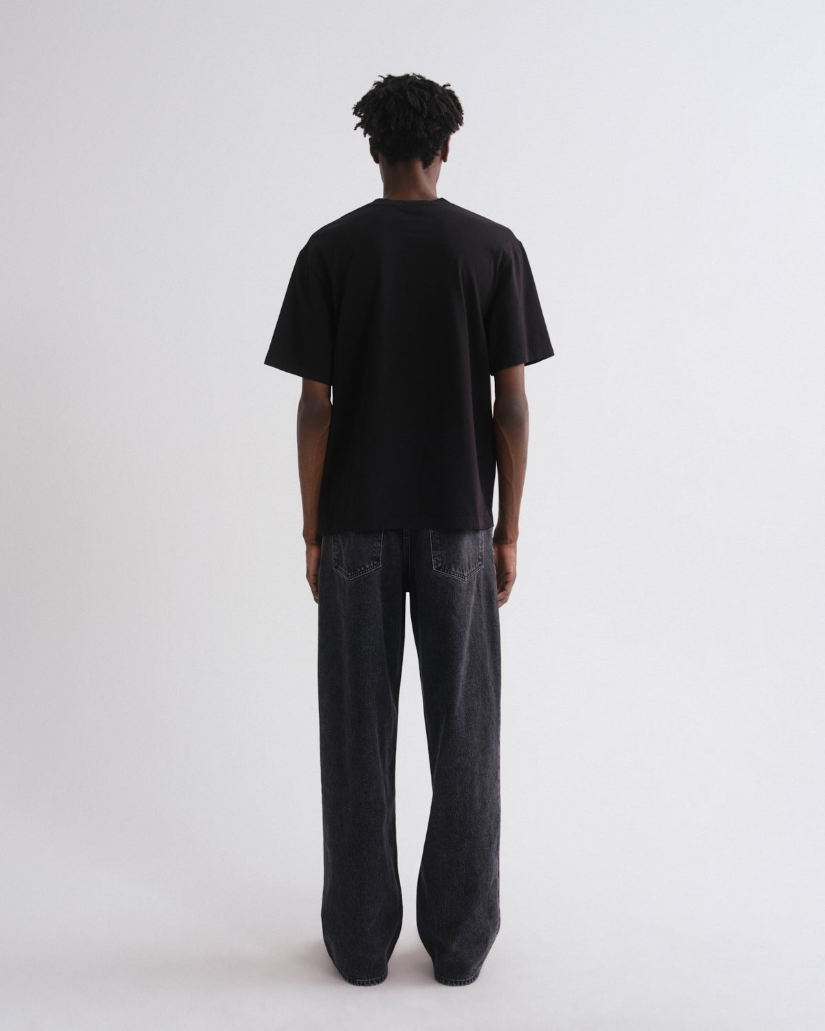 Person wearing a black t-shirt and dark pants on a white background
