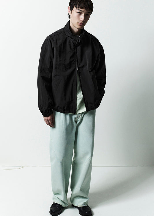 Person wearing a black jacket and light gray pants on a white background