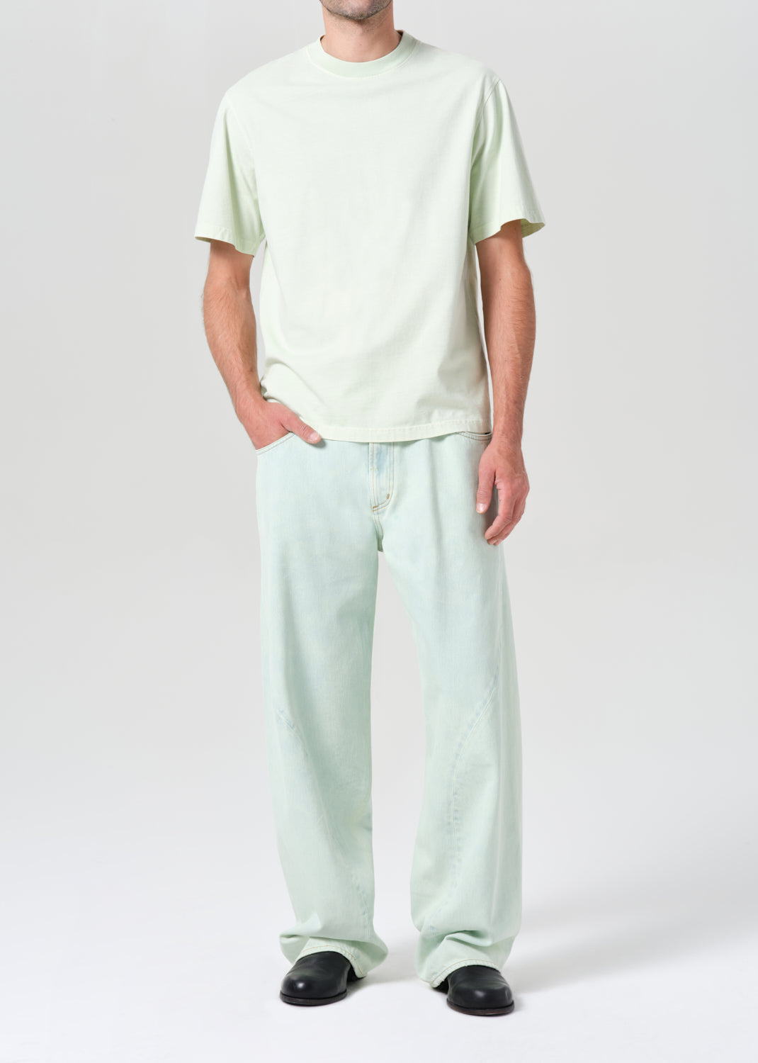 Person wearing a light green t-shirt and pants on a white background