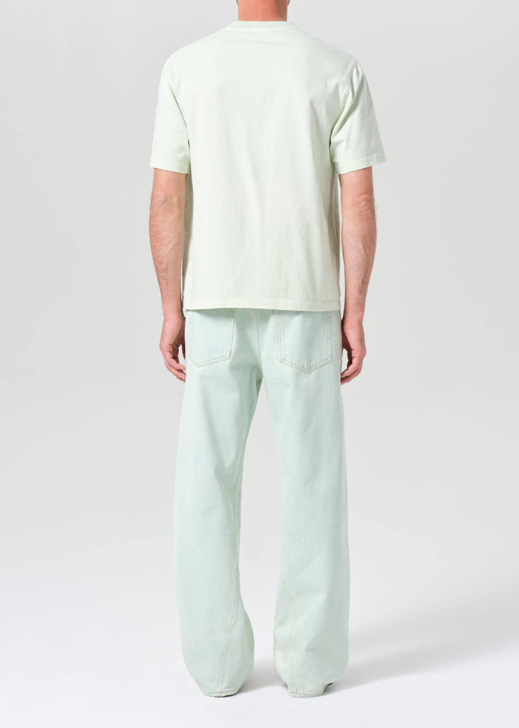 Person wearing a light green t-shirt and pants on a white background