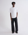 Person wearing a white t-shirt and black pants on a white background