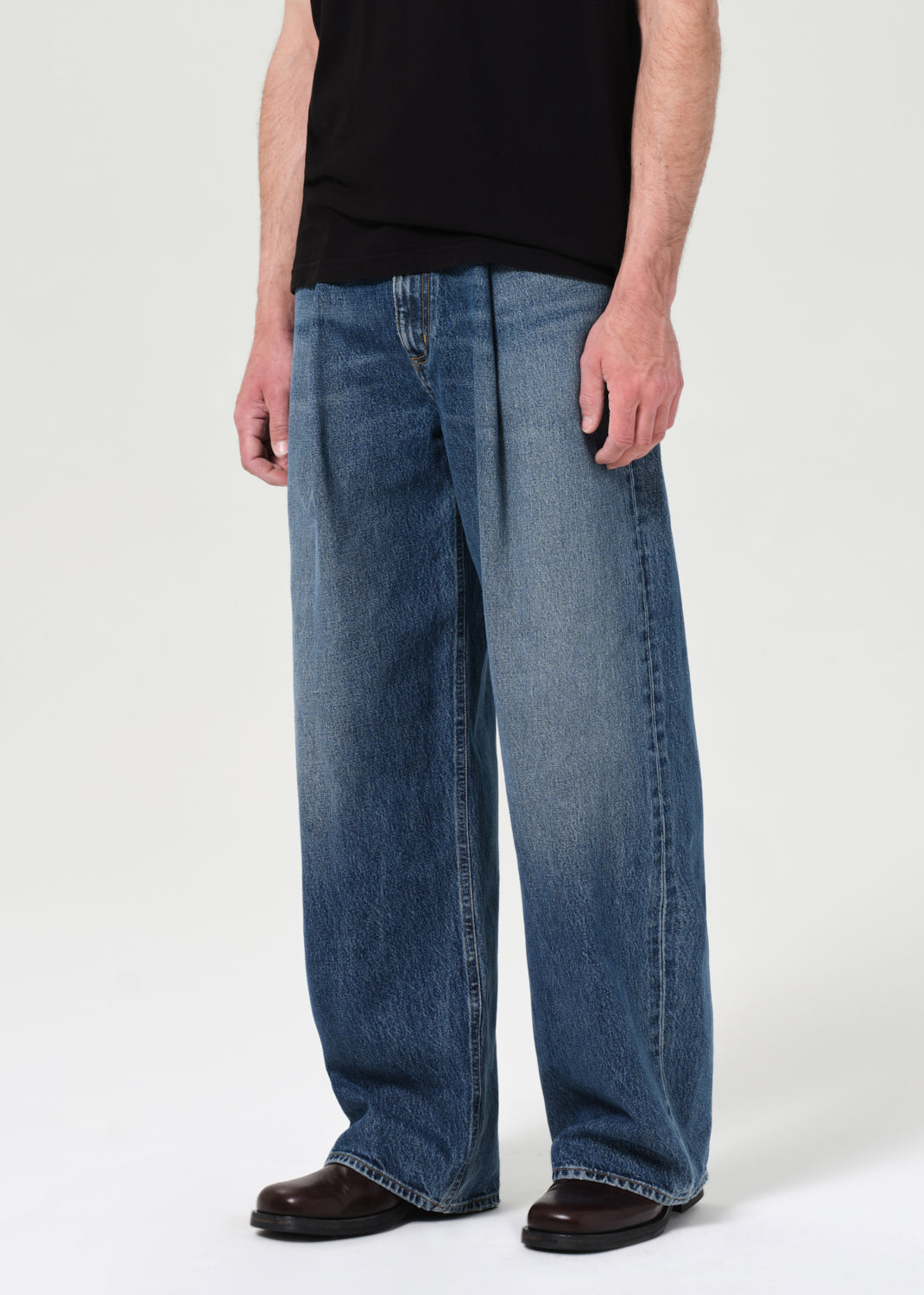 Person wearing blue jeans and a black shirt on a white background