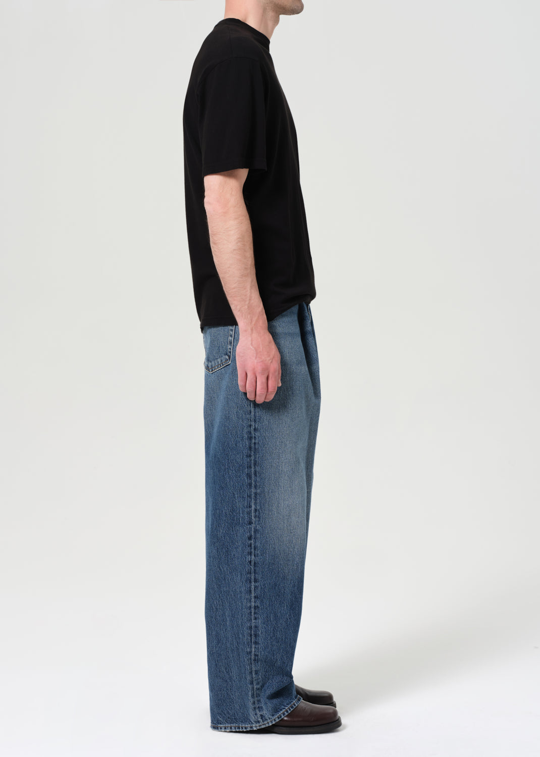 Person wearing a black t-shirt and blue jeans on a white background